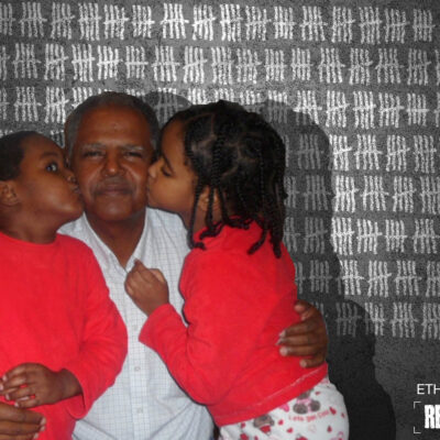 Image of Andy Tsege getting kissed by his children