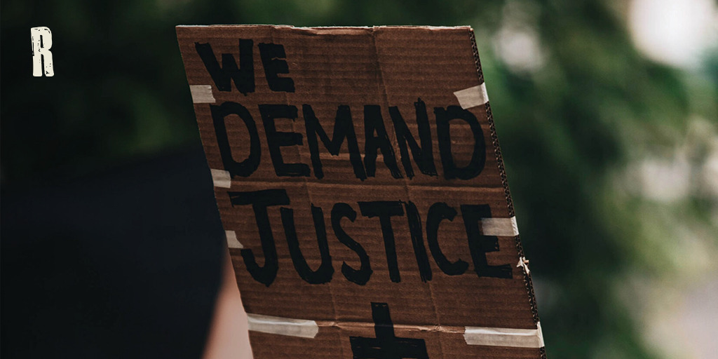 Stock image from UNSPLASH of person holding up a placard saying "Wed demand justice + change"