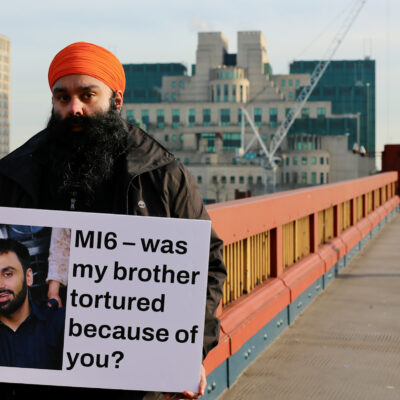 Gurpreet Singh Johal stands outside MI6 with a sign