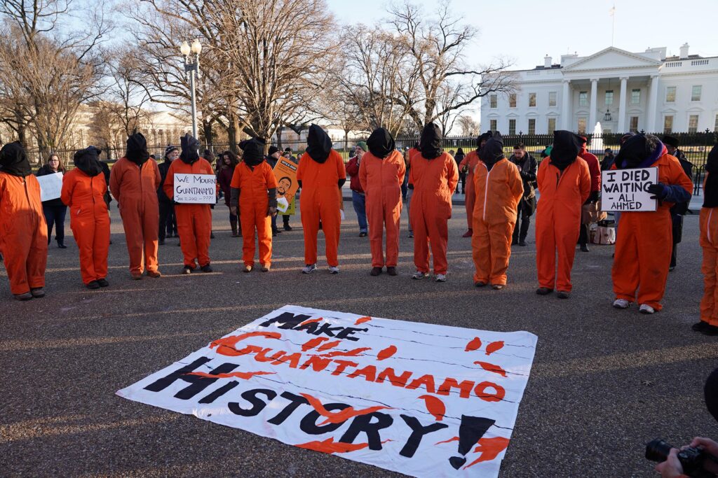 Background image of protesters calling for Guantanamo to be shut down in Washington DC, via Shutterstock